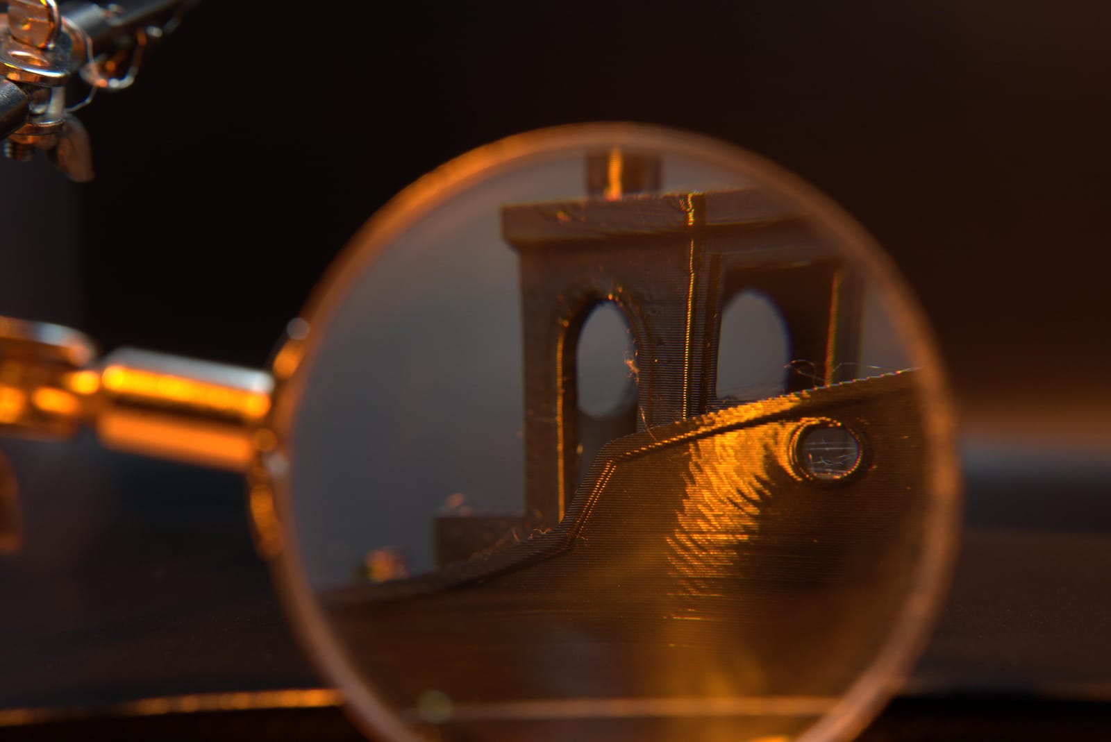 A loupe held over the filament boat's hull, the individual print layers clearly countable