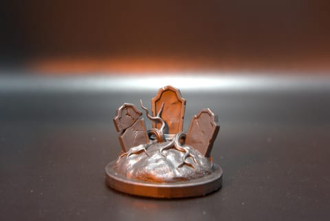 Copper-finished resin graveyard base with three headstones and roots crawling over the mound