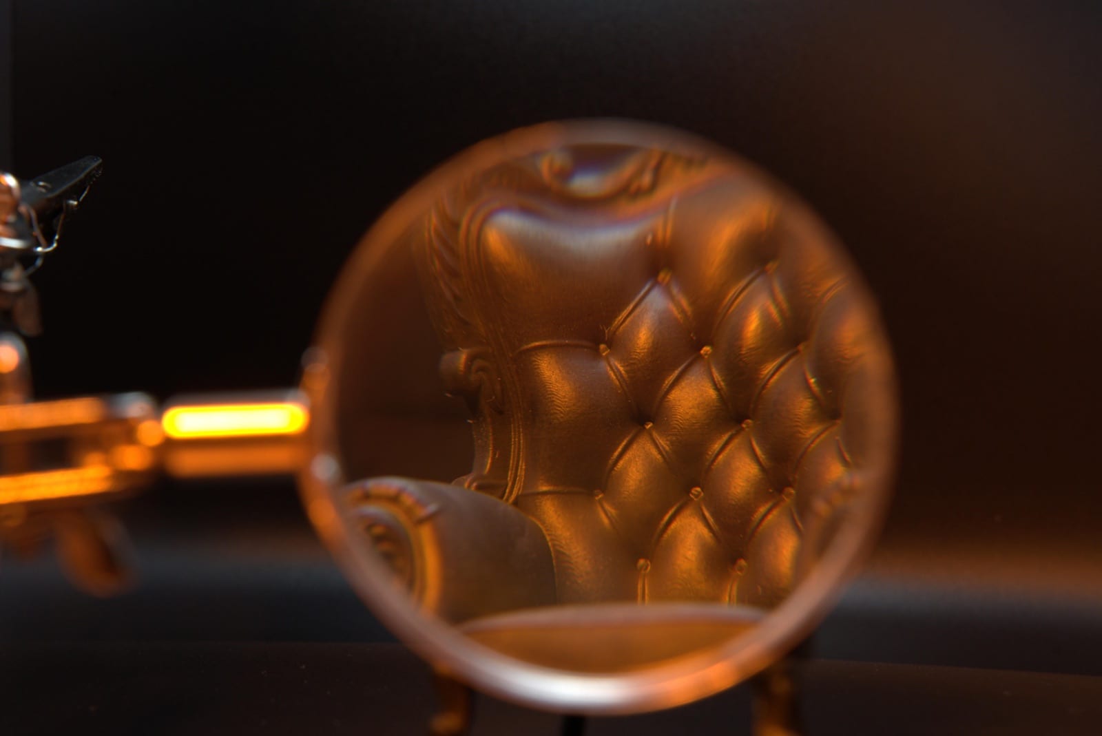 Magnifying glass over the miniature armchair's tufted cushion buttons