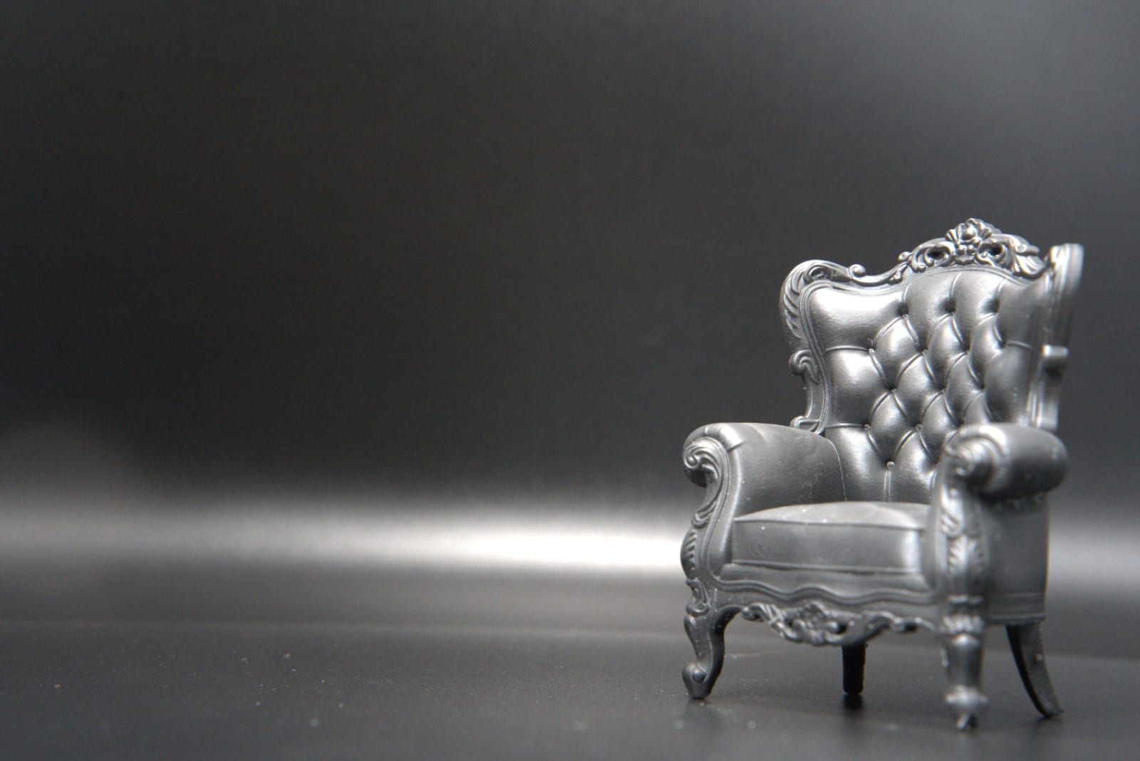 1:12 scale resin-printed tufted wingback armchair against a grey backdrop