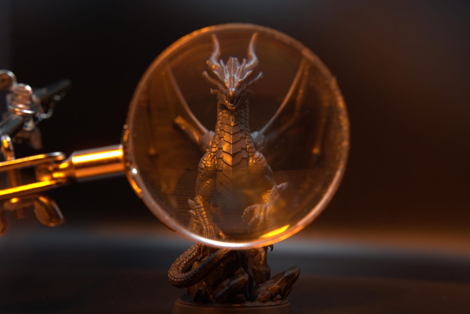Magnifying glass over the dragon miniature's head — no visible layer lines at 25 microns
