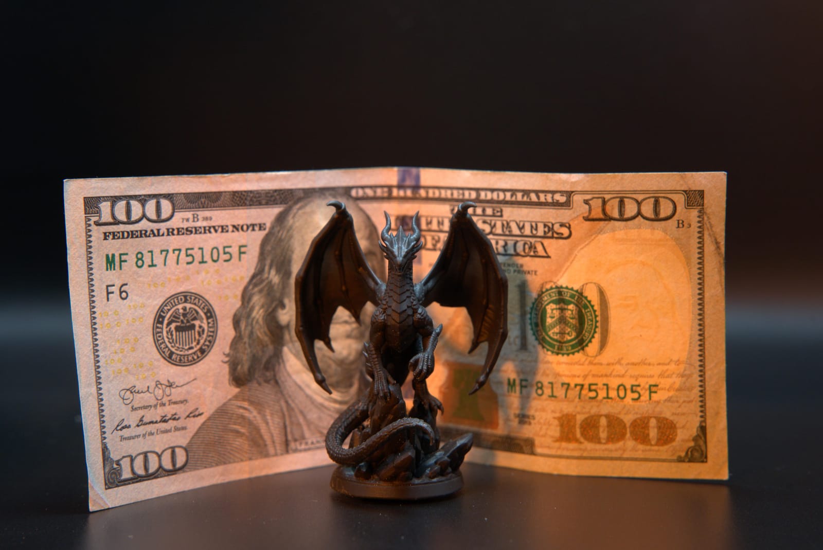The copper resin dragon miniature standing in front of a hundred-dollar bill, showing its true size