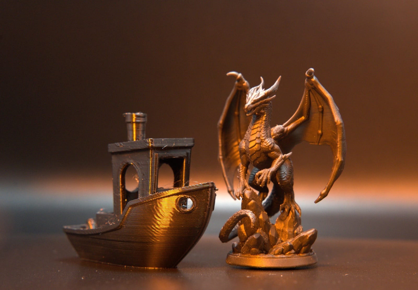 An FDM filament boat with visible layer lines beside a crisp SLA resin dragon, printed from comparable files